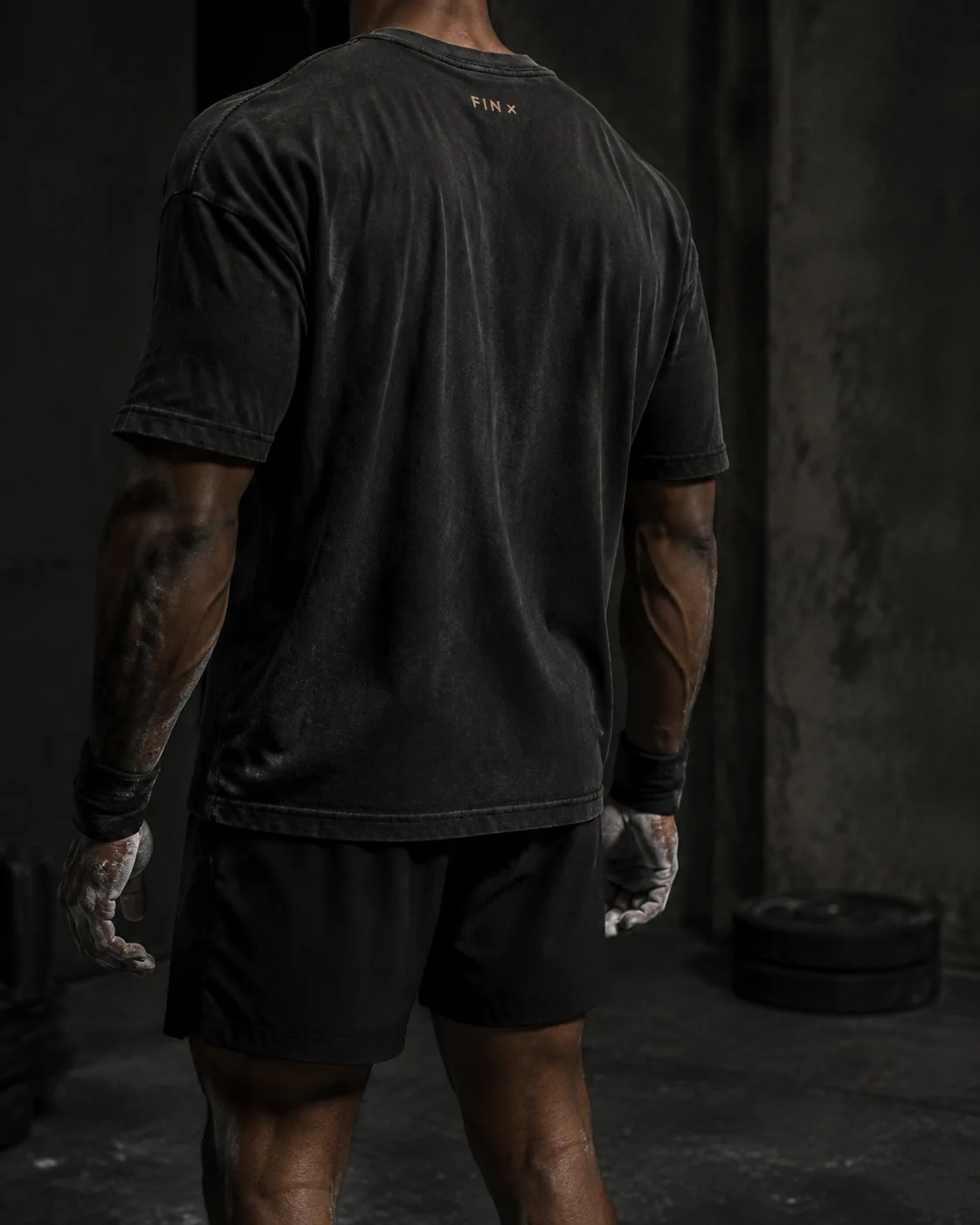 Original campaign concept: an athlete in a washed-black tee, facing the light in a concrete training space.