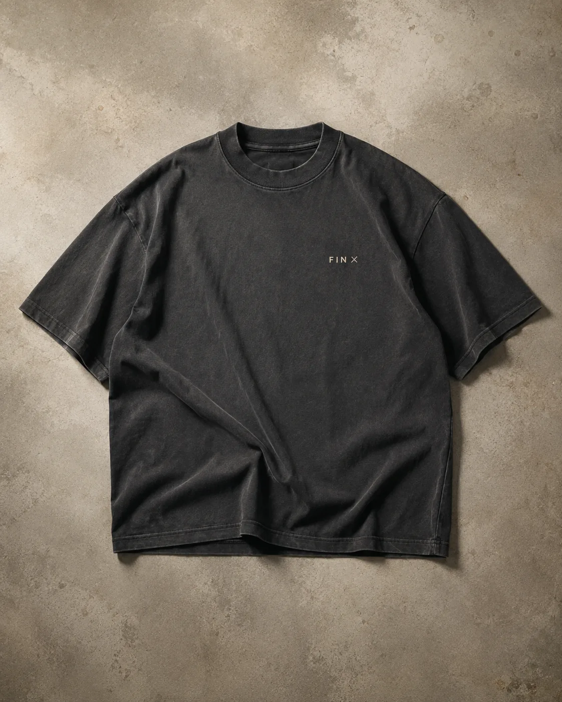 Design concept for a washed-charcoal oversized tee with a small FIN × chest mark. Final garment may differ.